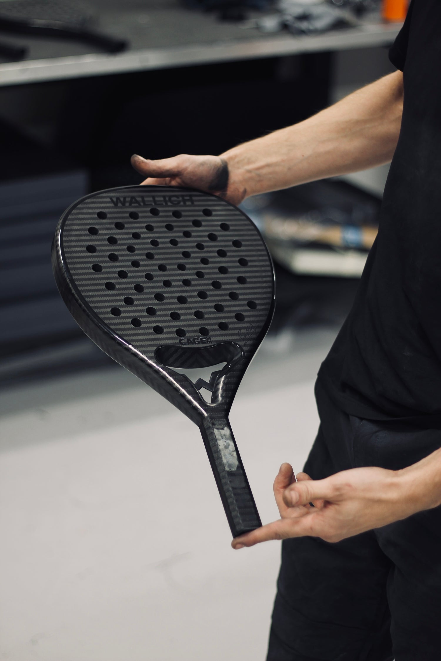 hands holding black padel racket