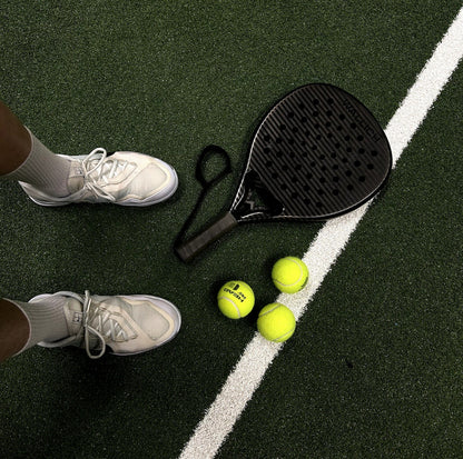 padel racket on green court with balls