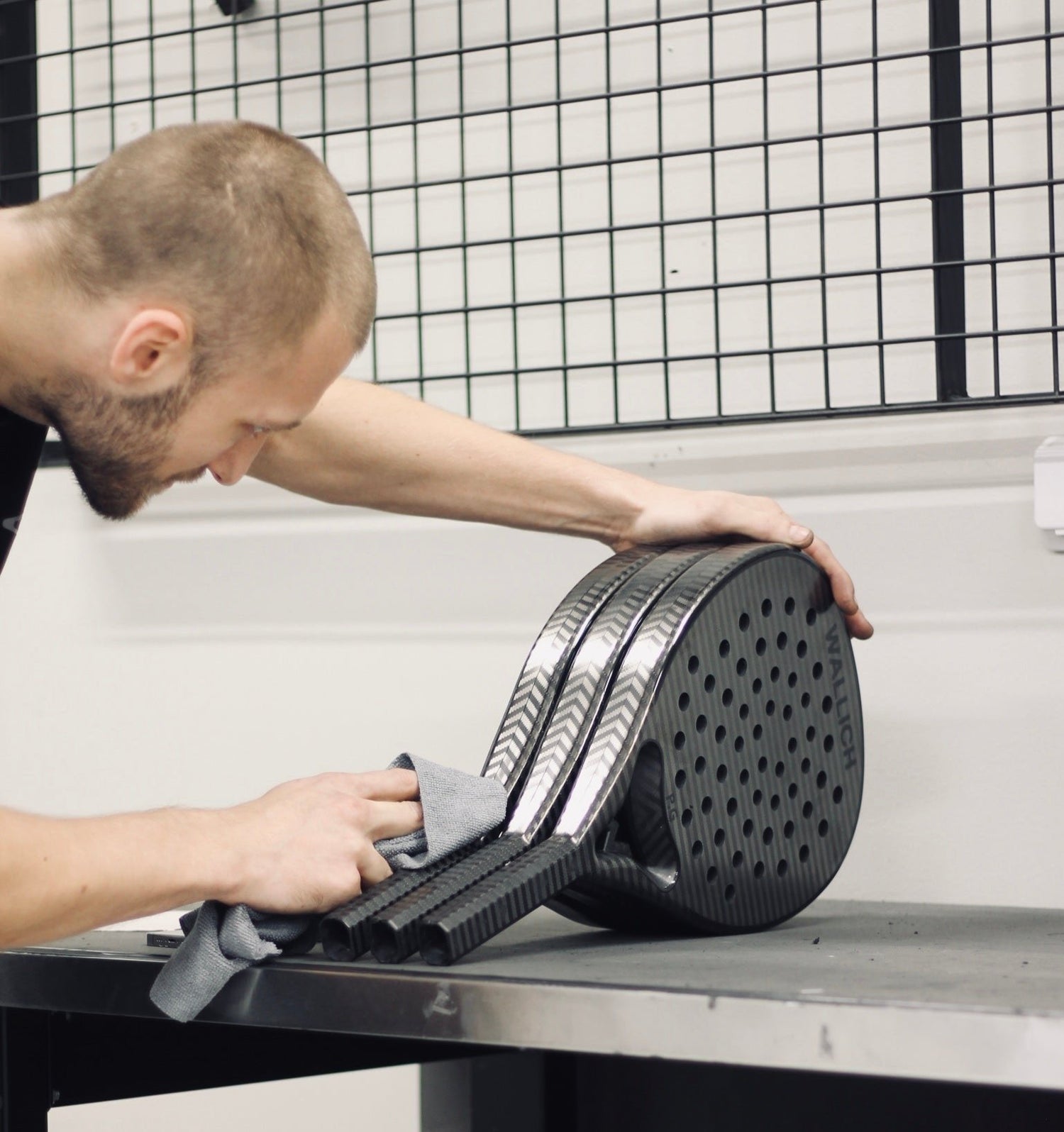 man polishing black padel rackets